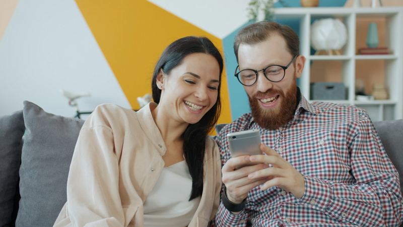 Two people on a sofa looking at a phone together